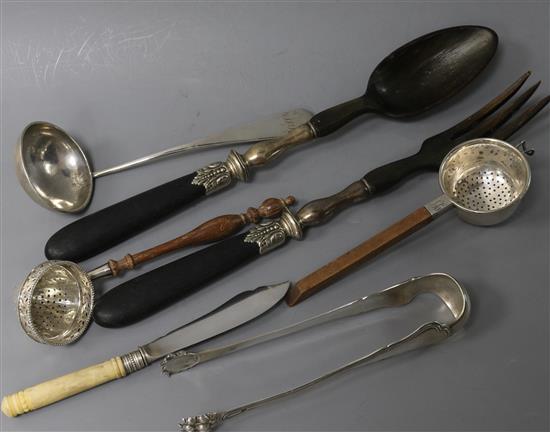 A pair of white metal mounted salad servers, two silver tea strainers, a pair of sugar tongs, a cream ladle & a butter knife (7)